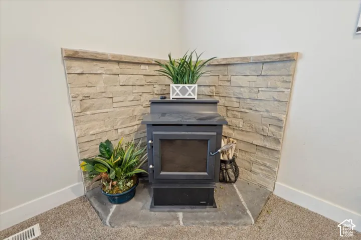 Corner wood-burning stove featuring a glass-front door, set against a stacked stone accent wall