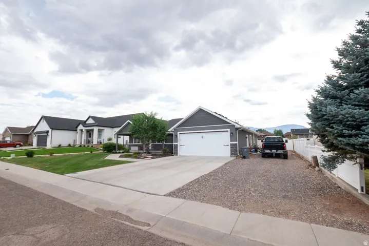 Contemporary gray siding residence with a white garage door, concrete driveway, and gravel parking area