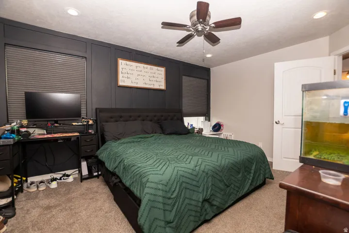 Bedroom featuring a paneled accent wall, neutral carpeting, a ceiling fan with light fixture, recessed lighting, and a white interior door