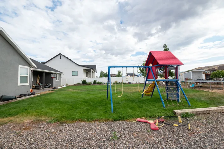 Expansive green lawn with a playset featuring slides, swings, and a climbing net