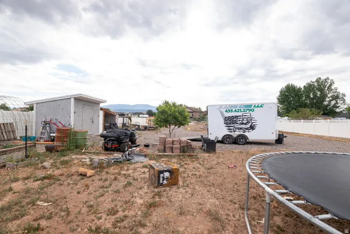 Expansive gravel area with a storage shed and white privacy fencing