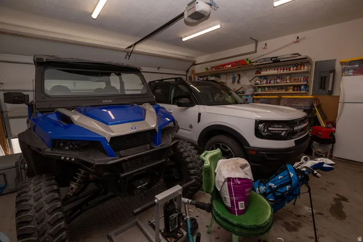 Attached garage featuring a concrete floor, built-in shelving, overhead fluorescent lighting, and an automatic garage door opener