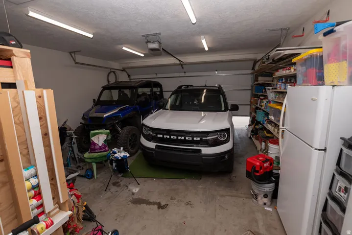 Attached garage with concrete flooring, fluorescent ceiling lighting, and overhead garage door