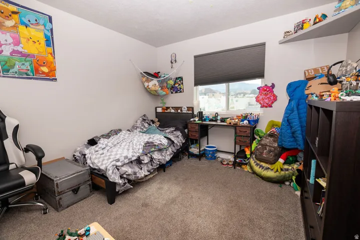 Carpeted room featuring a large window with roller shades, a built-in floating shelf, and neutral wall paint