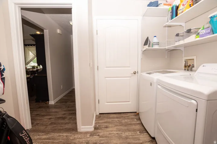 Dedicated laundry area featuring white shelving, light gray walls, wood-finish flooring, and a white interior door