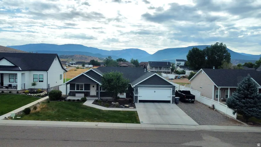 Contemporary ranch-style residence featuring a dark gray exterior, white trim, and a prominent attached garage with a white door