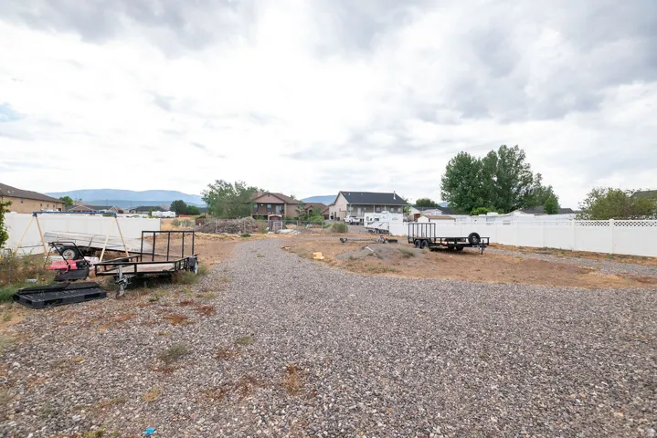 Gravel lot featuring a white perimeter fence and distant mountain range