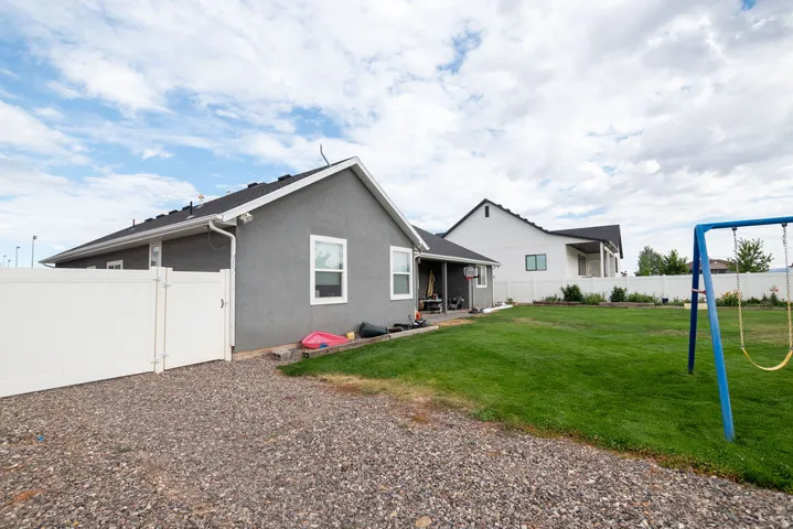 Expansive backyard featuring a manicured lawn, full privacy fencing, and a gravel perimeter
