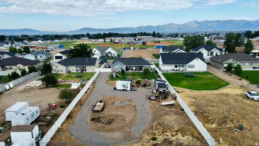Expansive gravel lot featuring a white vinyl fence and a mountain backdrop