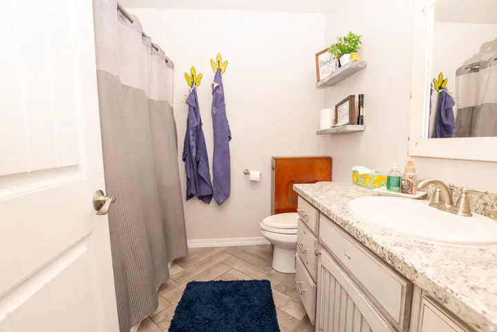 Bathroom featuring a single vanity with stone-finish countertop, undermount sink, and brushed nickel faucet