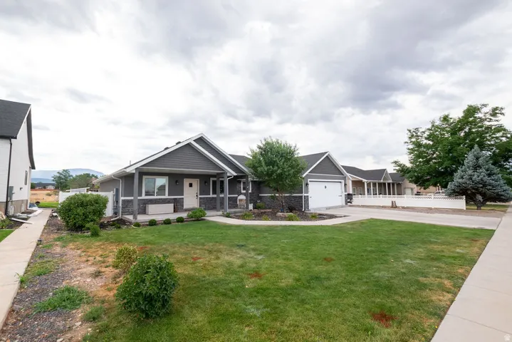 Single-story residence featuring gray siding and stone facade accents, a covered front porch, and an attached two-car garage