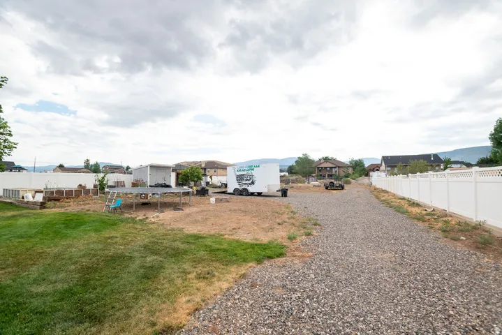 Expansive gravel driveway leading to a large, partially grassed yard