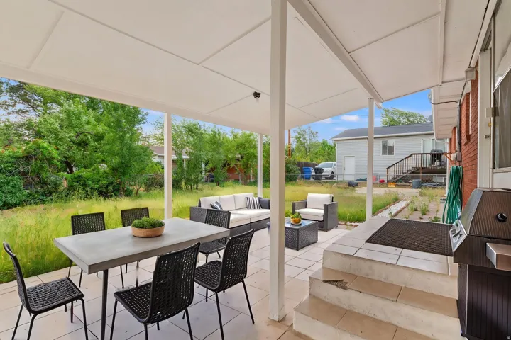 Covered patio with a tile floor, featuring a brick exterior wall and direct outdoor access w/ virtual staging