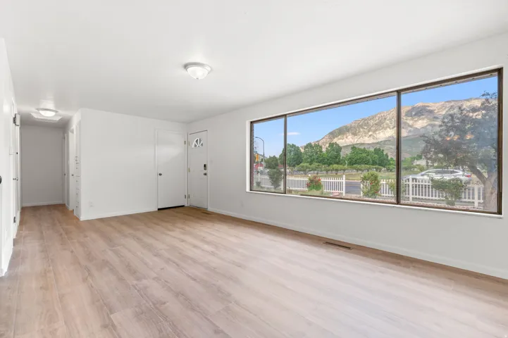 Expansive room featuring light wood-finish flooring, white walls, and a large multi-pane window