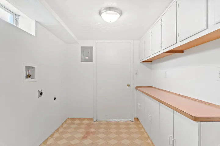 Laundry area featuring a utility sink connection, window, overhead flush-mount light fixture, built-in cabinetry, and countertop space