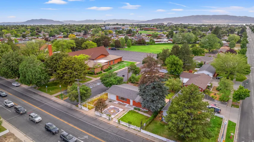 Residential property featuring an open front yard with a decorative hardscaped area and mature trees