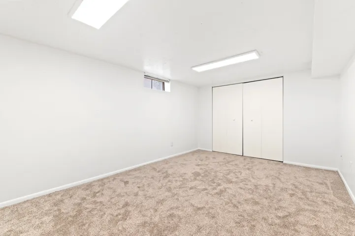 Carpeted room featuring white walls, a multi-panel bi-fold closet, and two overhead rectangular fluorescent light fixtures