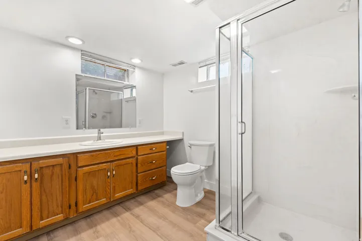 Full bathroom featuring a single vanity with wood cabinetry, a white countertop, and a recessed sink