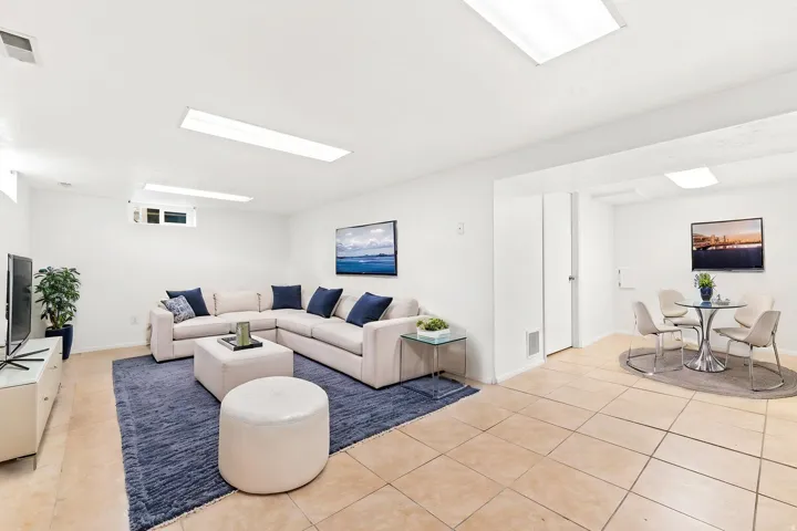 Spacious recreation room featuring recessed lighting, light-toned tile flooring, and a window for natural light w/ virtual staging