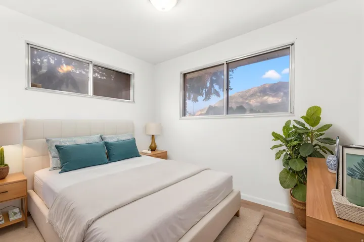 Bedroom featuring wood-finish flooring, white walls, and multiple windows w/ virtual staging