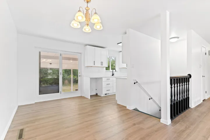 Open-concept living space featuring wood-finish flooring and a contemporary chandelier
