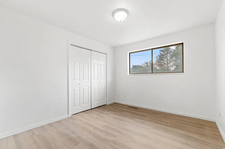 Bright interior room featuring wood-finish flooring, white walls, and a ceiling-mounted light fixture