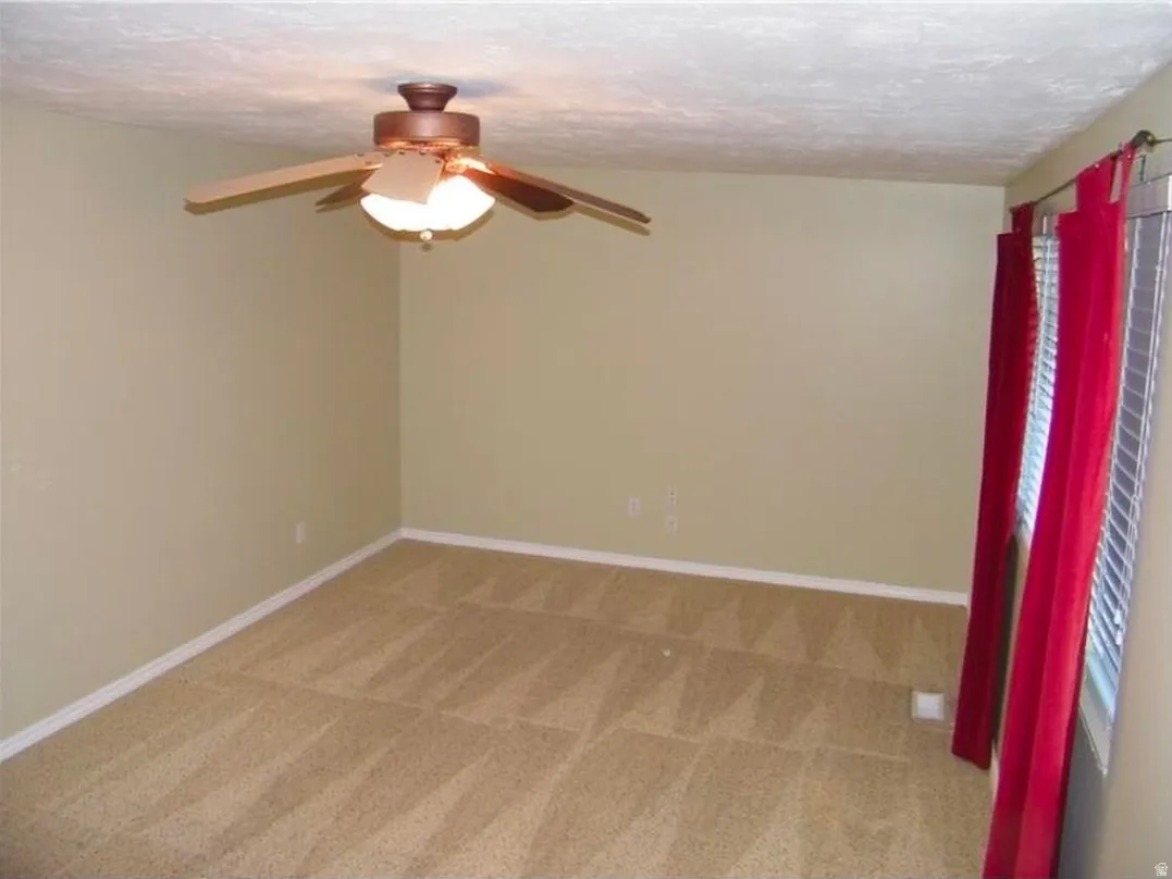 Carpeted room with a ceiling fan light fixture