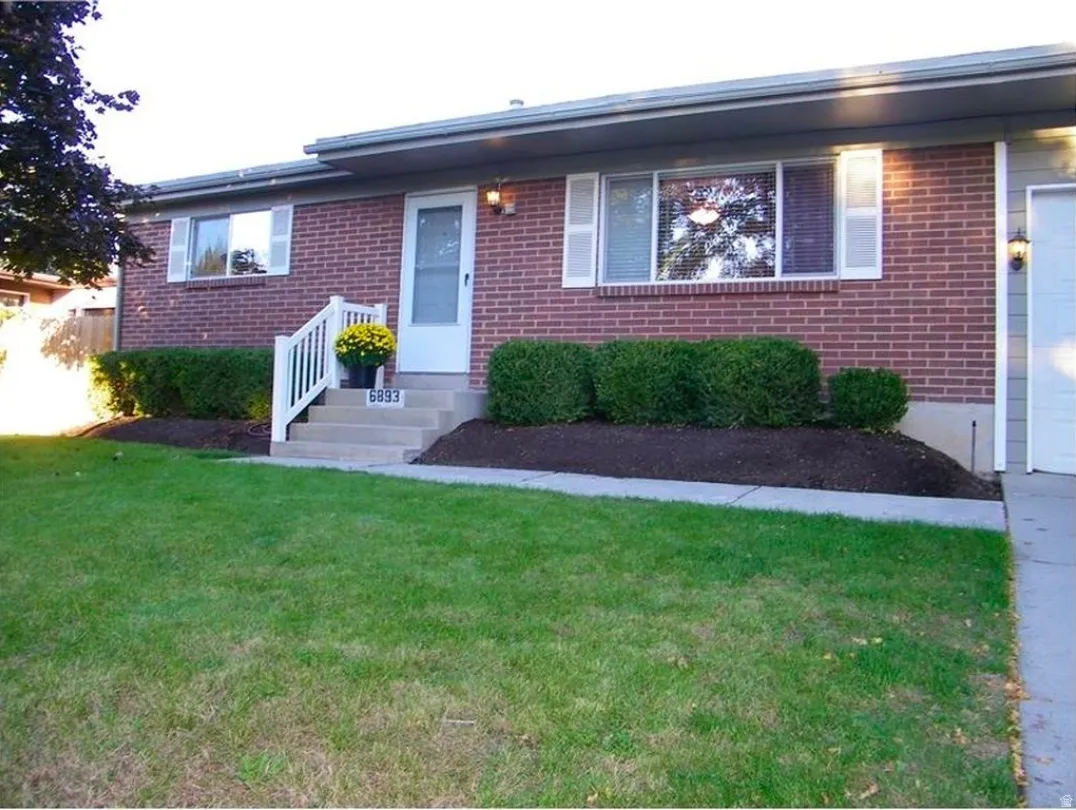 Brick exterior facade featuring a front entrance with concrete steps and white railings