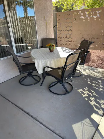 Concrete patio featuring a decorative privacy screen, textured exterior wall, and sliding glass door