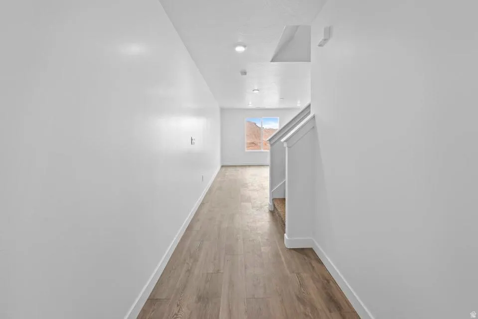 Bright interior hallway featuring wood-finish flooring, white walls, and recessed lighting