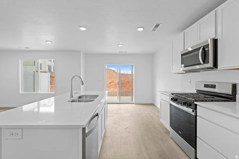 Modern kitchen featuring white cabinetry, light wood-finish flooring, recessed lighting, and stainless steel appliances
