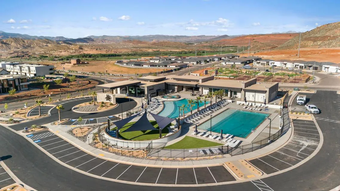 Community clubhouse featuring an expansive pool deck with multiple swimming pools and a shaded artificial turf area