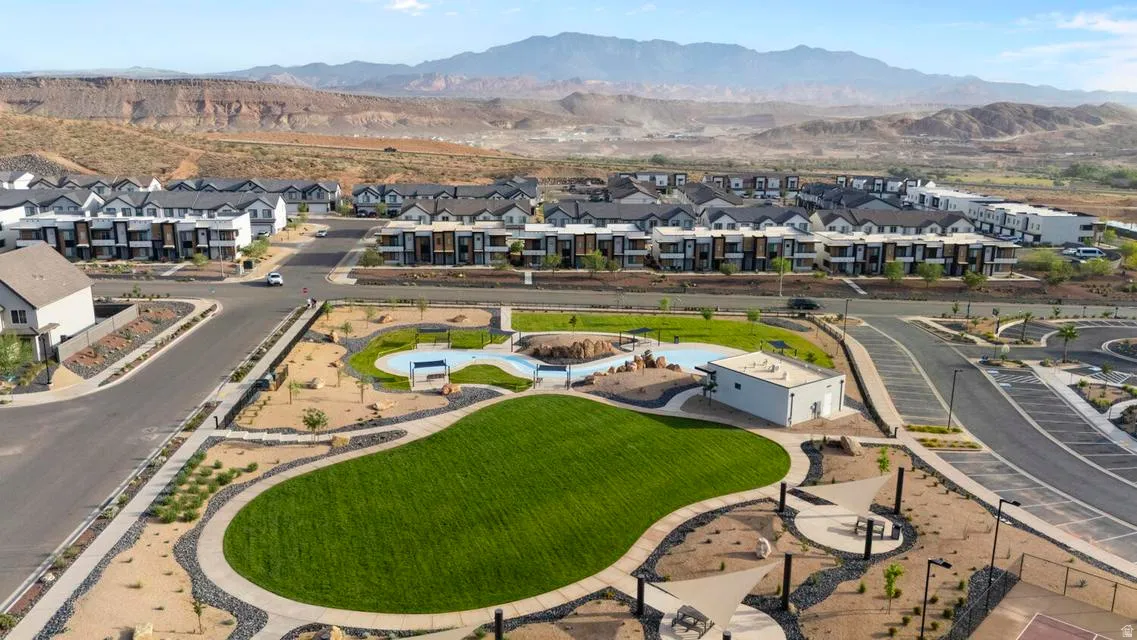 Community green space featuring a manicured lawn, a swimming pool, and a recreational building