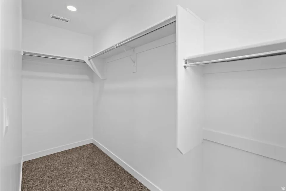 Walk-in closet featuring white walls, baseboards, and shelving with hanging rods