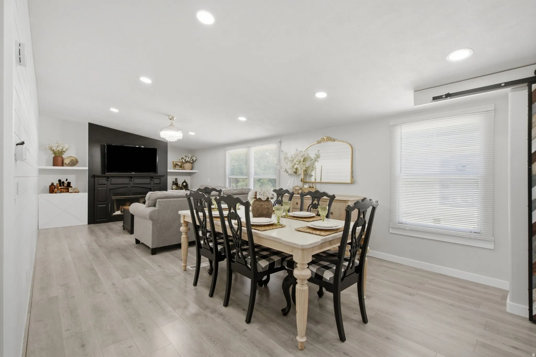 Open-concept living area featuring wood-finish flooring, recessed lighting, and a prominent fireplace with built-in shelving