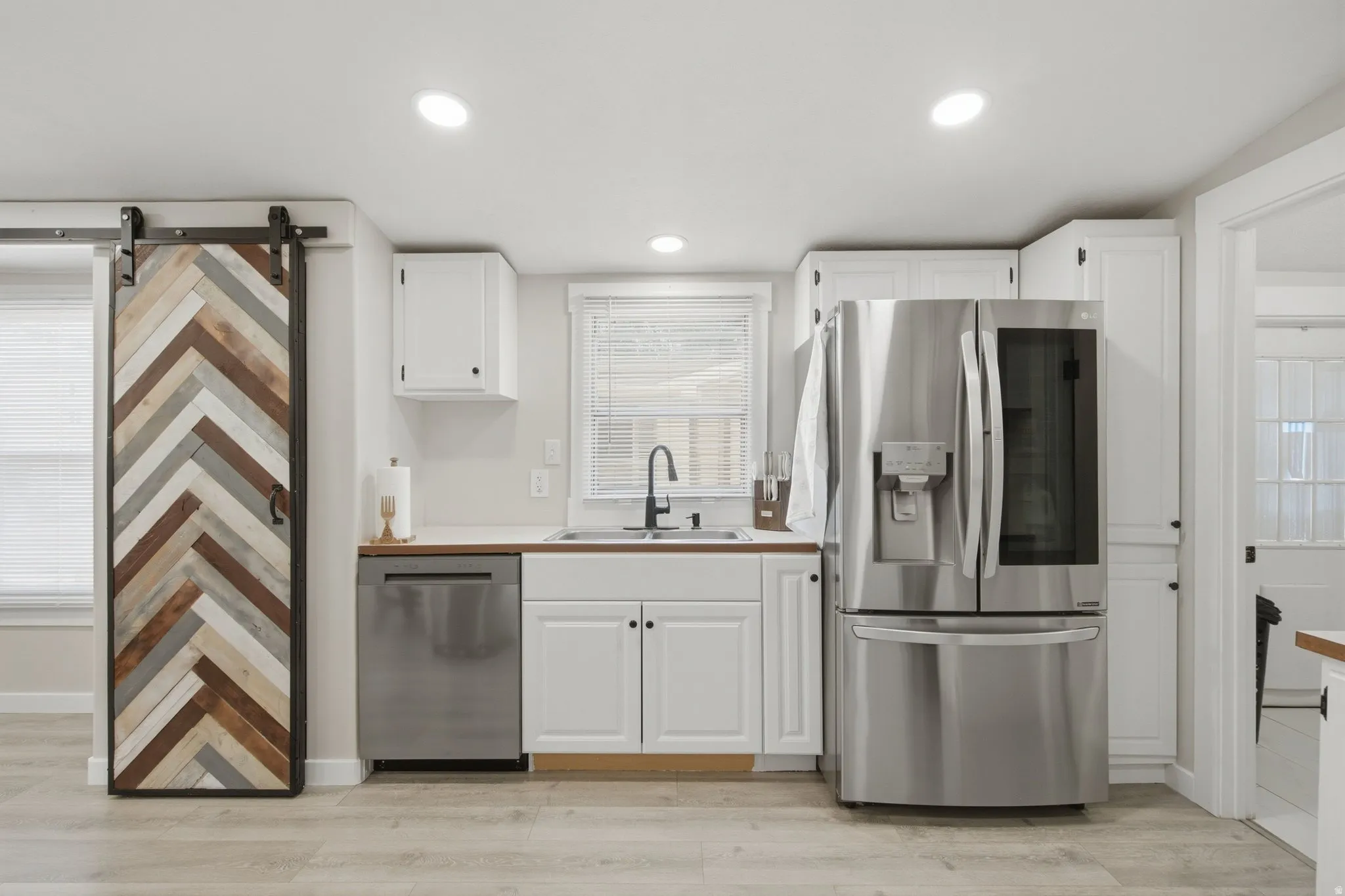 Kitchen featuring white cabinetry, wood-finish countertops, stainless steel appliances, and wood-finish flooring