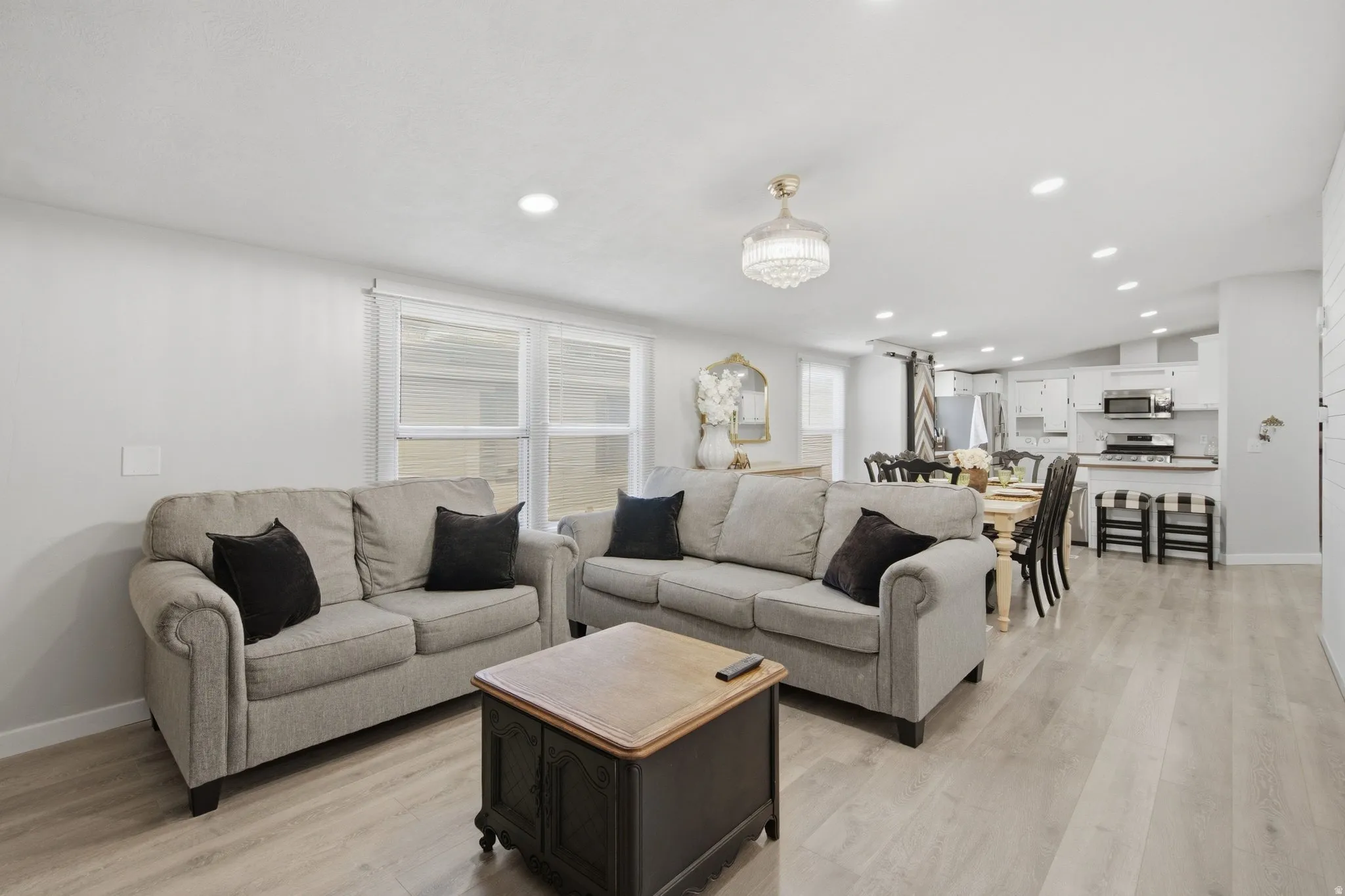 Open-concept living space featuring wood-finish flooring, recessed lighting, and a white color palette