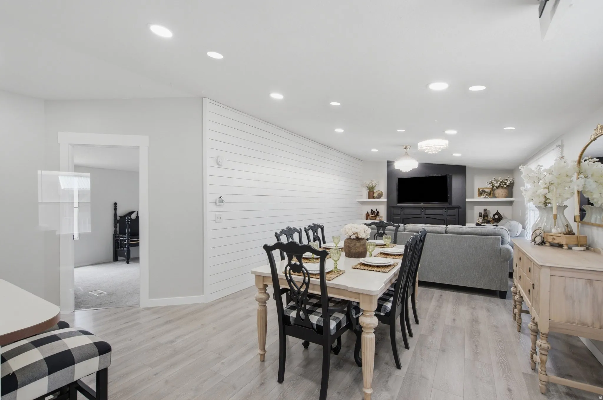 Open-concept living area featuring light wood-finish flooring, recessed lighting, and a shiplap accent wall