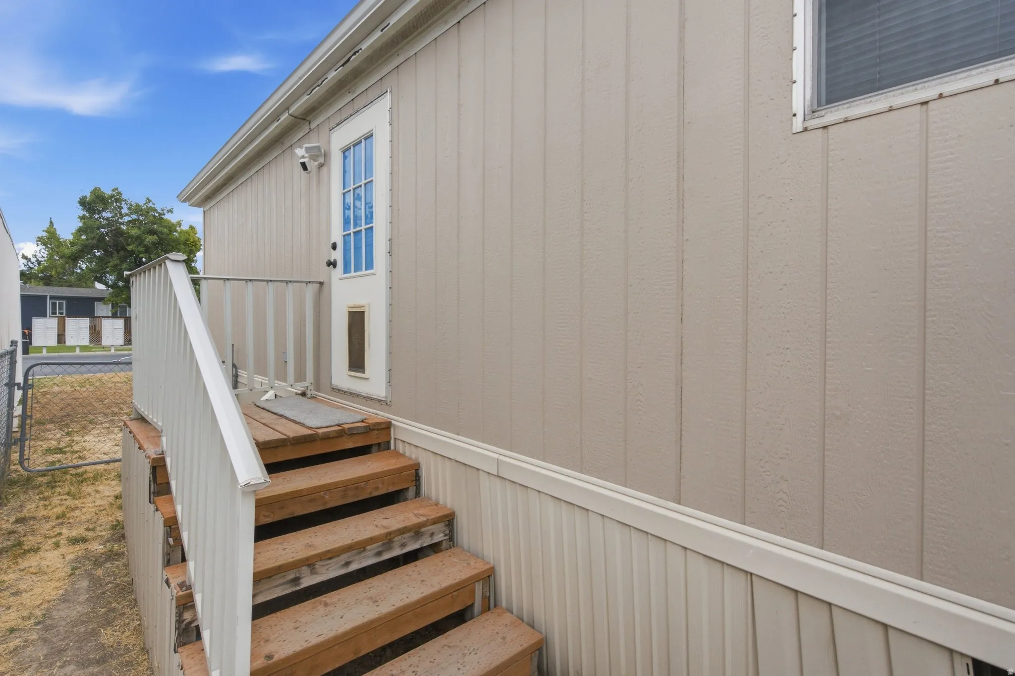 Exterior entry featuring wood steps, a white handrail, and beige vertical panel siding