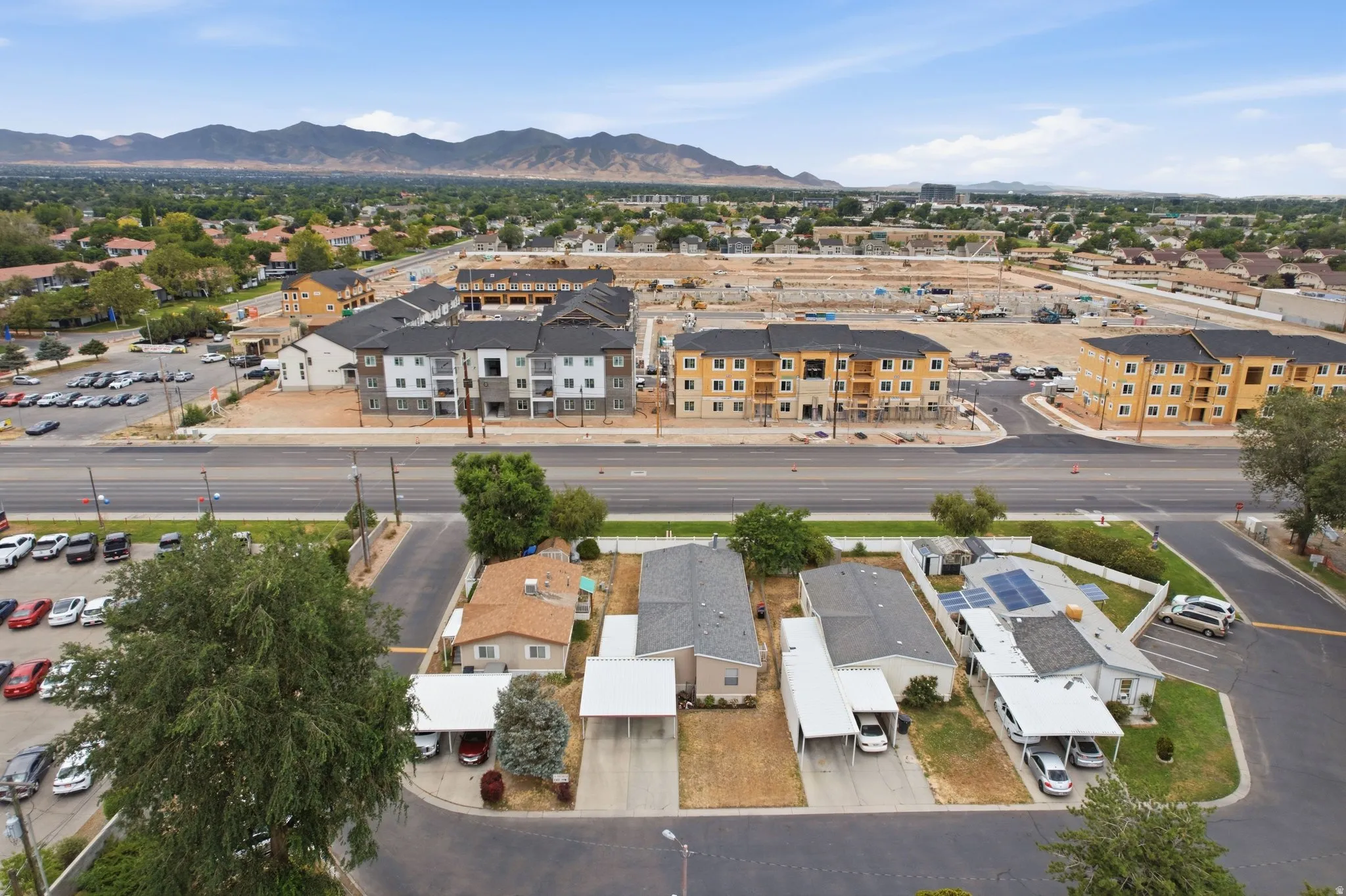 Aerial perspective featuring a residential street with single-story homes and multi-story apartment buildings under construction