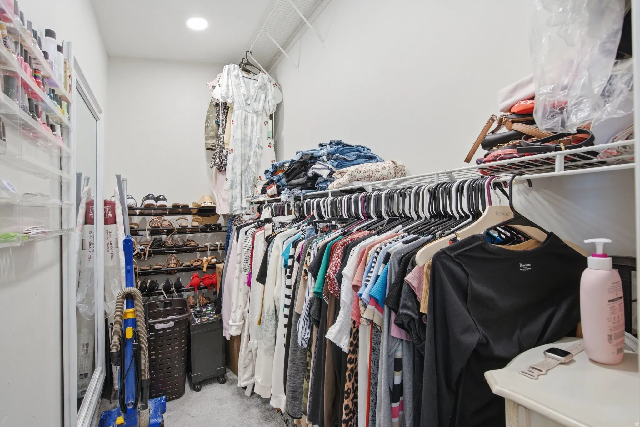 Walk-in closet featuring built-in wire shelving, overhead lighting, and abundant hanging space