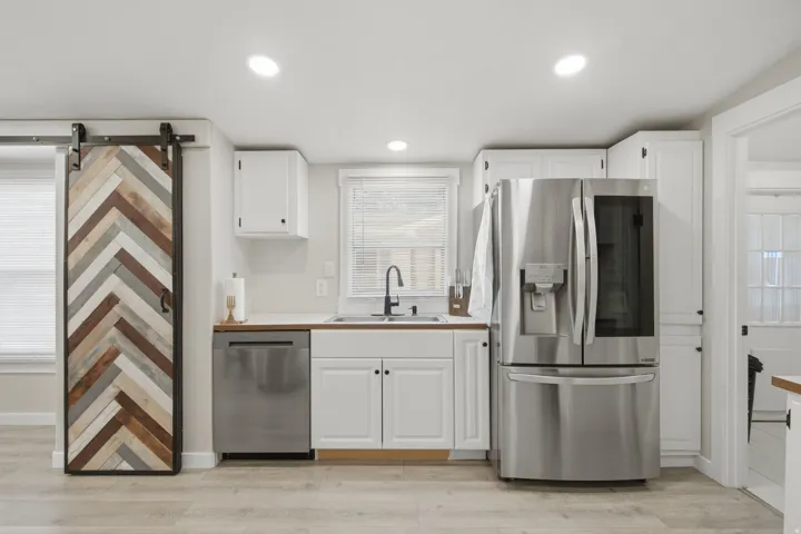 Kitchen featuring white cabinetry, wood-finish countertops, stainless steel appliances, and wood-finish flooring