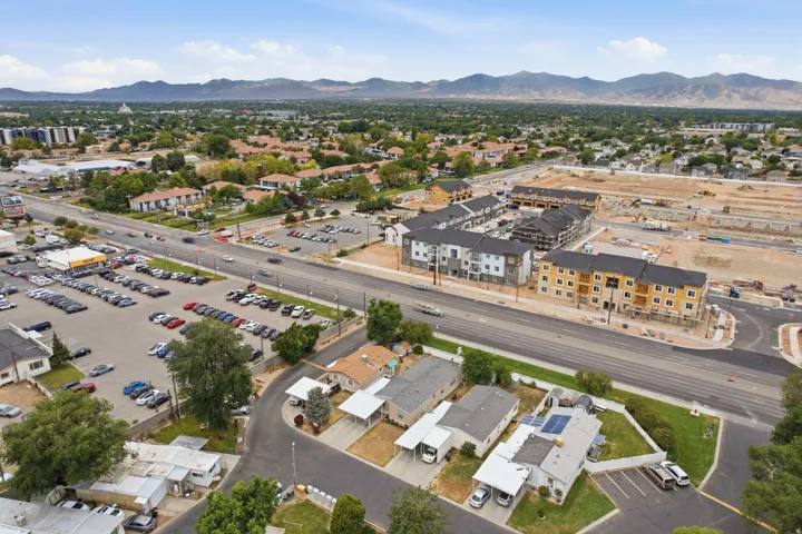 Expansive aerial view showcasing diverse residential and commercial properties, including new construction multi-story buildings, established single-story homes, and a commercial parking lot