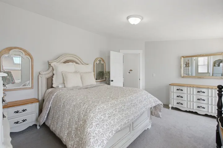 Carpeted bedroom featuring light gray wall paint, a ceiling-mounted light fixture, and a white door with black hardware