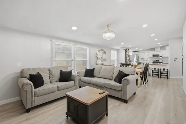 Open-concept living space featuring wood-finish flooring, recessed lighting, and a white color palette