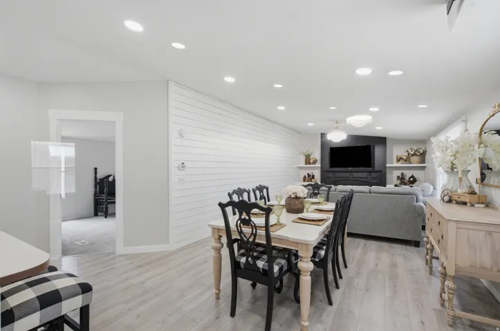 Open-concept living area featuring light wood-finish flooring, recessed lighting, and a shiplap accent wall