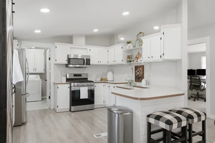 Kitchen featuring white cabinetry, light wood-finish countertops, stainless steel appliances, and wood-finish flooring
