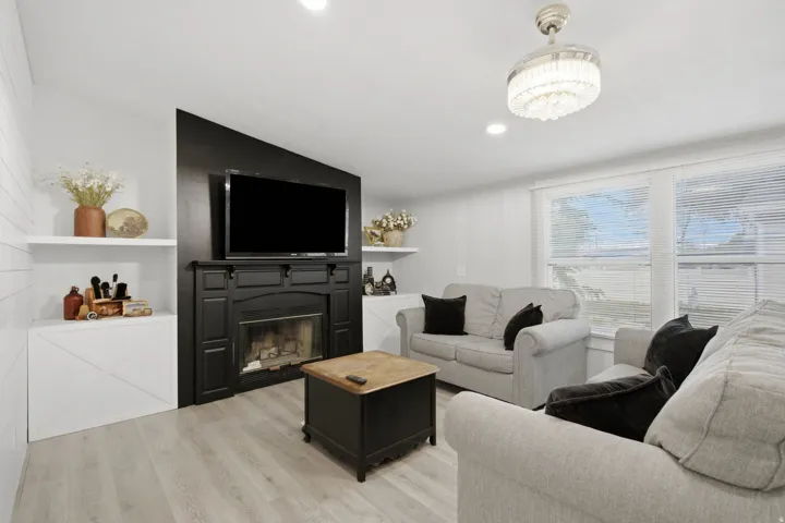Living area featuring a black fireplace with mantle and a mounted television