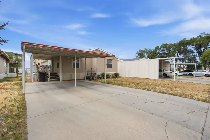 Concrete driveway with an attached carport, featuring a metal roof and support posts