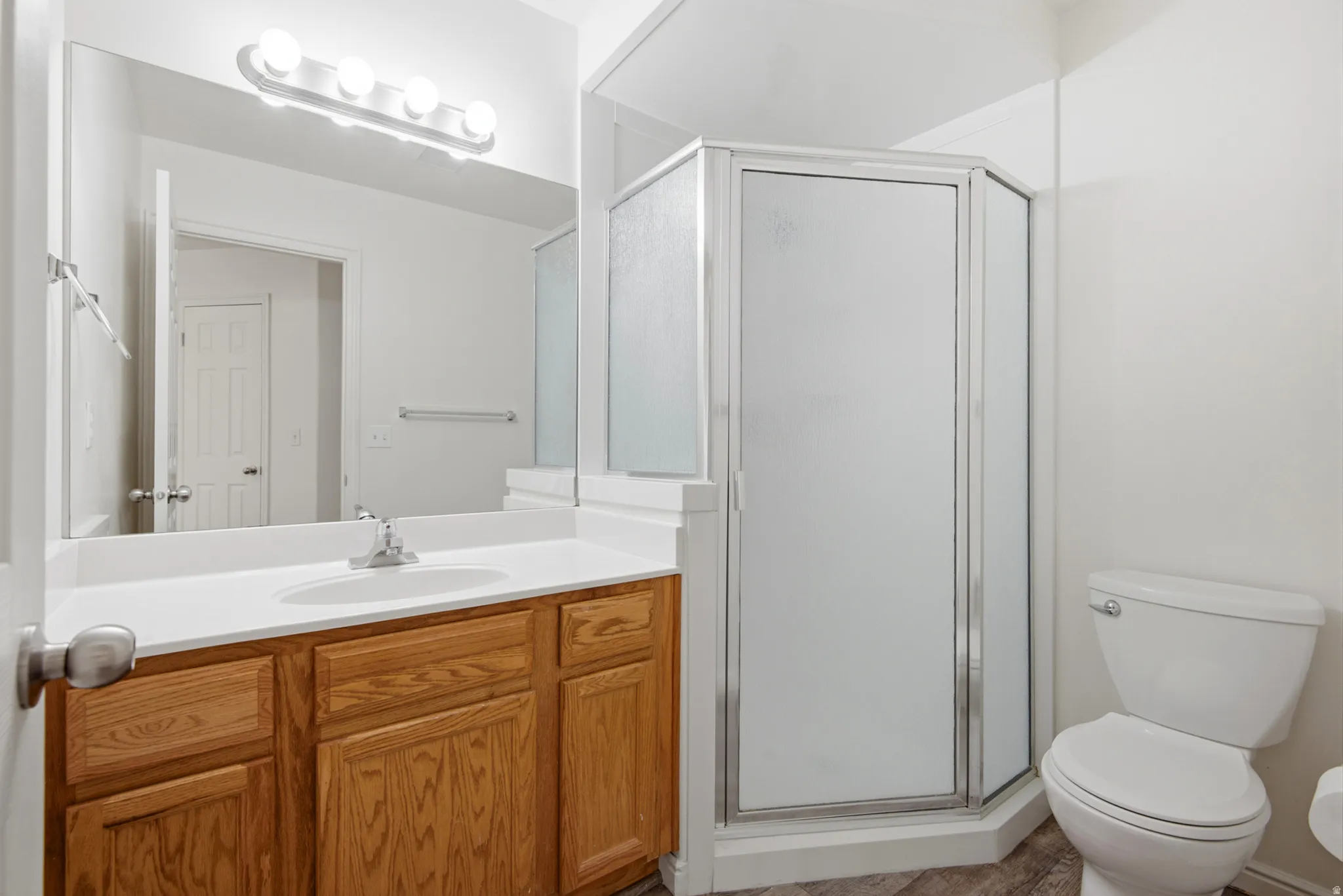 Bathroom featuring a light wood-finish vanity with an integrated sink, a large wall mirror, and a contemporary vanity light fixture